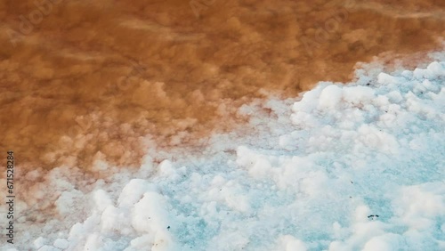 Mineralogy. Shore of hypersalted lake (self-settling salt lake) with deposition of salt crystals (solar salt). Red-brown water is determined by bacterias Dunaliella salina and Salinibacter ruber photo