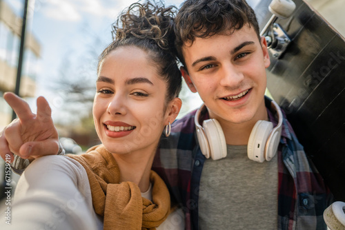 Young man and woman teenager couple take selfies by modern building