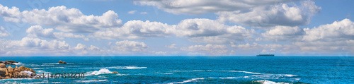 Landscape banner of a scenic ocean view in Camps Bay, Cape Town in South Africa. Panoramic scenery of the beach and waves rolling in from the sea against a blue cloudy sky in summer