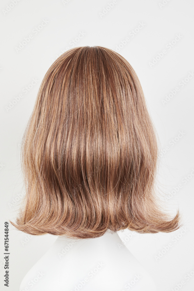 Natural looking dark brunet wig on white mannequin head. Middle length brown hair on the plastic wig holder isolated on white background, back view. Natural looking dark brunet wig on white mannequin head. Middle length brown hair on the plastic wig holder isolated on white background, back view.