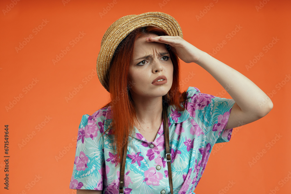 Close up of woman in hat standing holding hand over forehead looking for something with upset tired face, isolated on orange background. Portrait of female traveler. Close up of woman in hat standing holding hand over forehead looking for something with upset tired face, isolated on orange background. Portrait of female traveler.