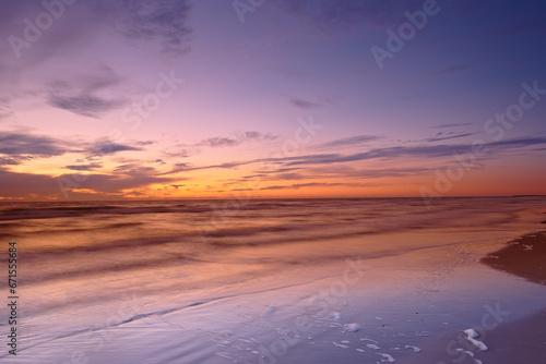 Seascape and landscape of a beautiful sunset on the west coast of Jutland in Loekken, Denmark. Sun setting on the horizon on an empty beach at dusk over the ocean and sea in the evening