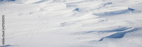 Snow texture. Wind sculpted patterns on snow surface. Wind in the tundra and in the mountains on the surface of the snow sculpts patterns and ridges. Arctic, Polar region. Winter panoramic background.