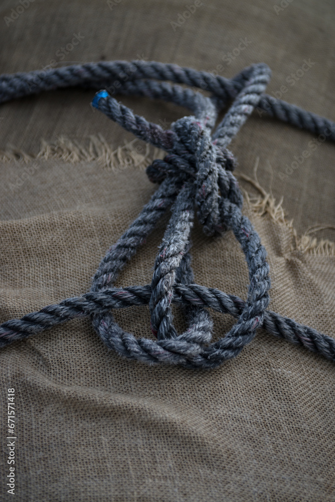 Black ship's rope tied in a sea knot on a cargo burlap