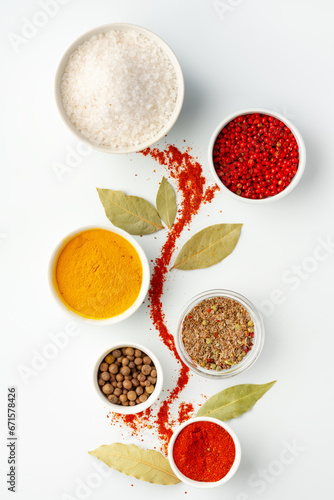 Bowls with spices and cooking ingredients on white background