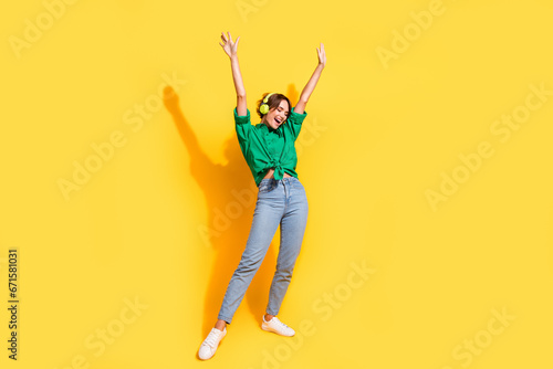 Full length photo of funky cool lady wear green shirt earphones enjoying songs dancing isolated yellow color background