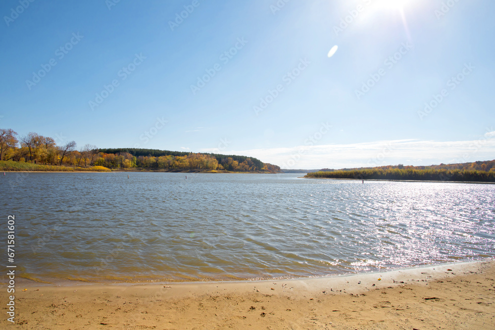 Autumn lake landscape with waves in the water, fall trees, and sun flare. Photo was taken on a fall day in Iowa. 
