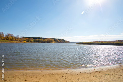 Autumn lake landscape with waves in the water  fall trees  and sun flare. Photo was taken on a fall day in Iowa. 