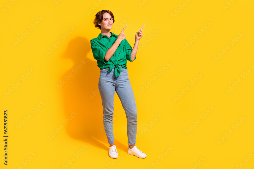 Fototapeta premium Full length photo of pretty positive lady wear green shirt showing two fingers empty space isolated yellow color background