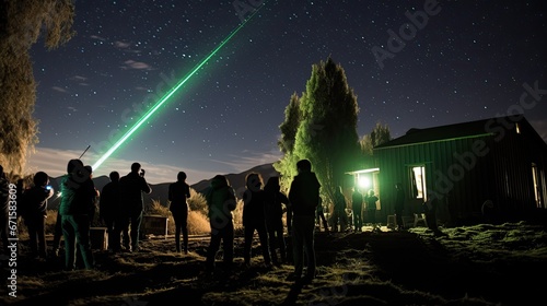 amateur astronomer  standing next to a telescope uses a green laser pointer to show a constellation to Iranian tourists taking part a training session to observe meteors  at an eco resort 