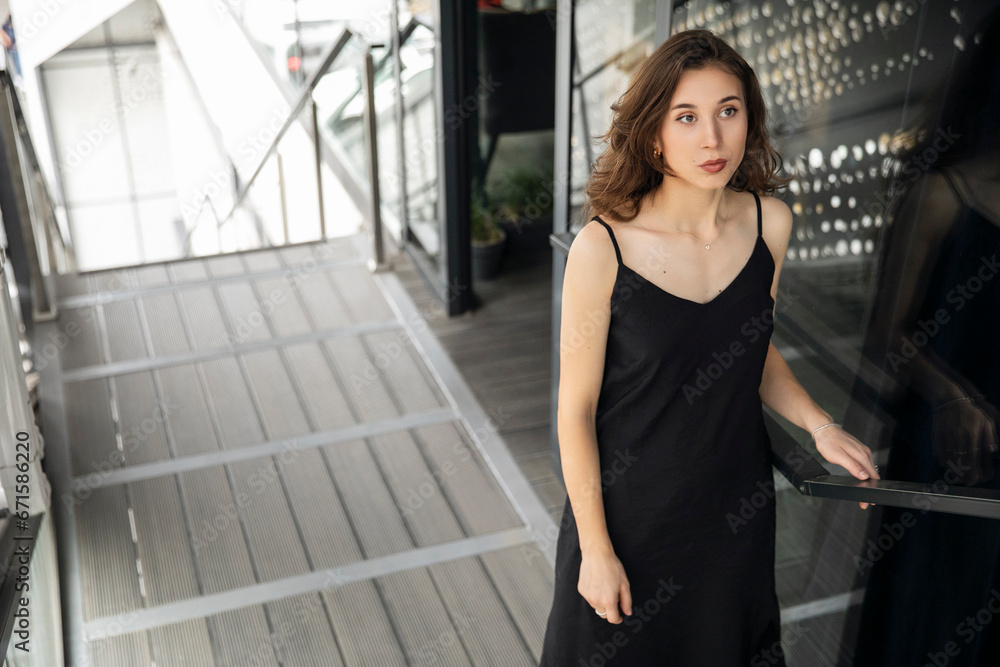 Portrait of a young woman in black dress, posing near building. Copy space. Portrait of a young woman in black dress, posing near building. Copy space.
