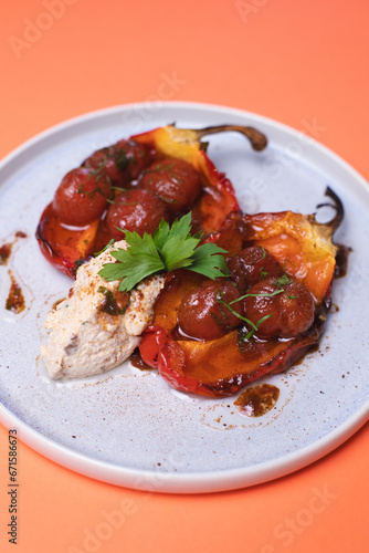 A hearty lunch of peppers stuffed with tomatoes on an orange background.