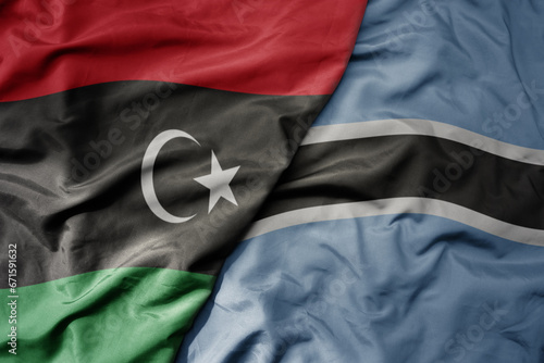 big waving national colorful flag of libya and national flag of botswana .