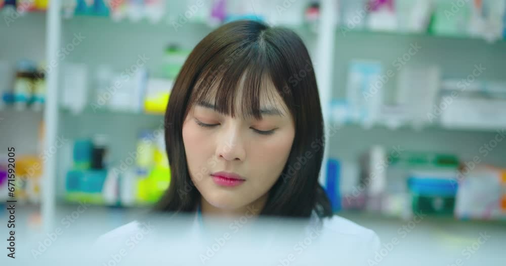 Young asian female pharmacist using computer in pharmacy shop. She research drug information at pharmacy shop. Young asian female pharmacist using computer in pharmacy shop. She research drug information at pharmacy shop.