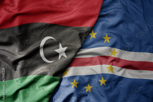 big waving national colorful flag of libya and national flag of cape verde .