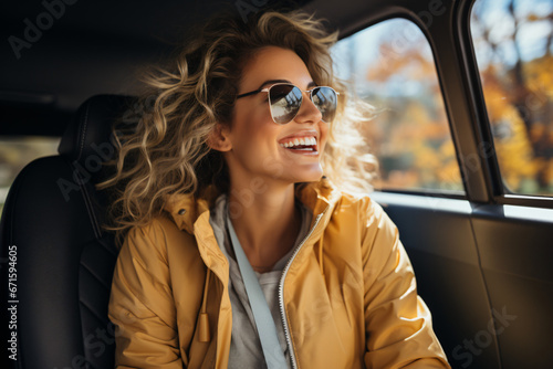 Beautiful young woman driving a car on a road trip in autumn. Beautiful young woman driving a car. Happy blonde young woman posing in the car on a driver place 