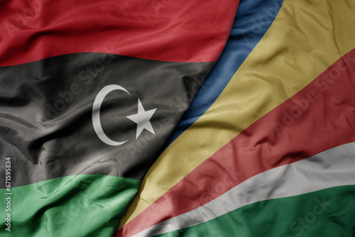 big waving national colorful flag of libya and national flag of seychelles .