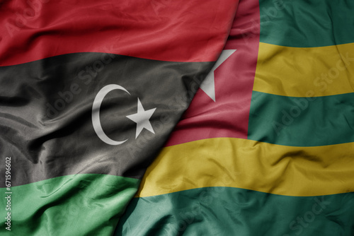 big waving national colorful flag of libya and national flag of togo .
