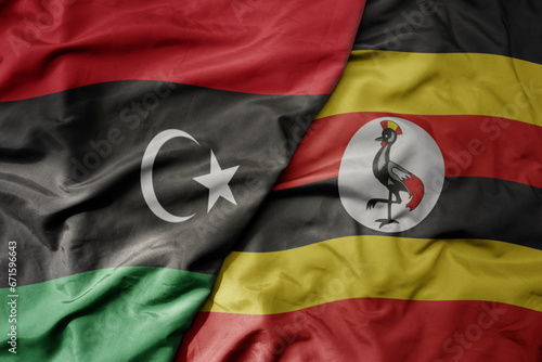 big waving national colorful flag of libya and national flag of uganda .