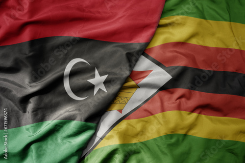 big waving national colorful flag of libya and national flag of zimbabwe .