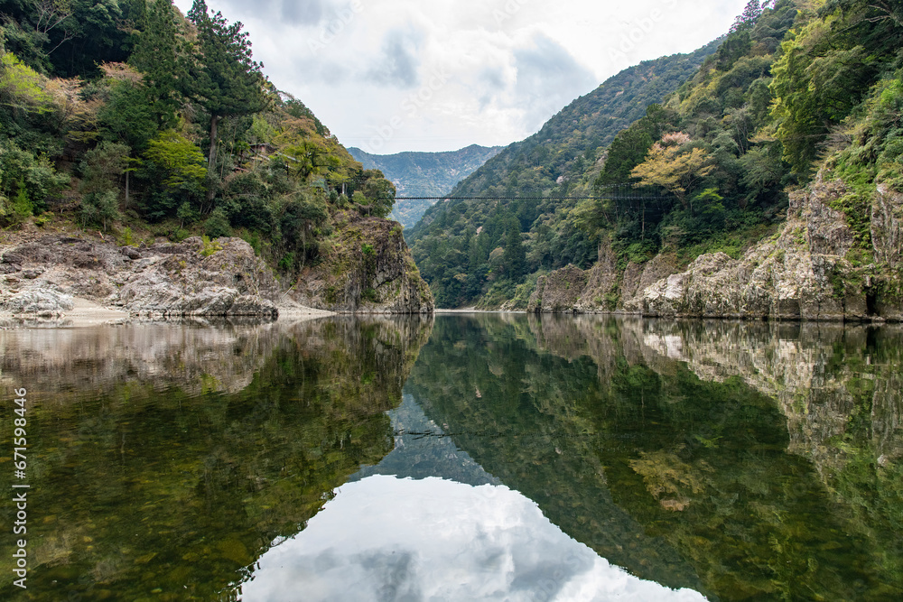 Perfect reflection of rock formations, ravines and cliffs of Doro-kyo Gorge in Shingu, Wakayama, Japan in tranquil water of Kitayama River in Kii mountain range in Yoshino-Kumano National Park
