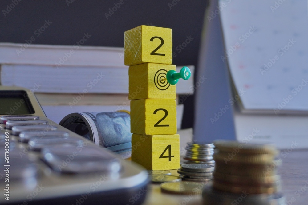 Φωτογραφία Wooden cube with number 2024 and pushpin surrounded by money and calculator