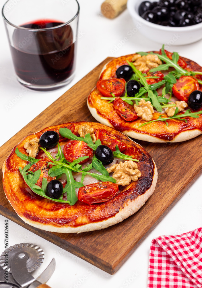Two pizzas with mozzarella cheese, nuts, arugula, tomatoes and olives. Italian food. Vegetarian food. Two pizzas with mozzarella cheese, nuts, arugula, tomatoes and olives. Italian food. Vegetarian food.