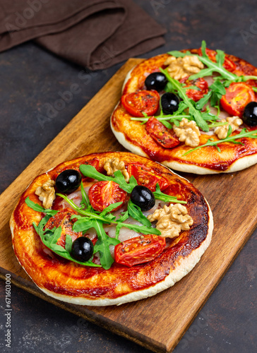 Two pizzas with mozzarella cheese, nuts, arugula, tomatoes and olives. Italian food. Vegetarian food.