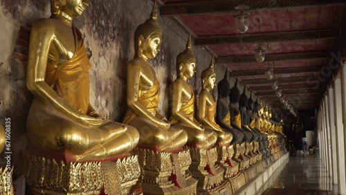 Golden yellow robed Buddha statues sitting in rows