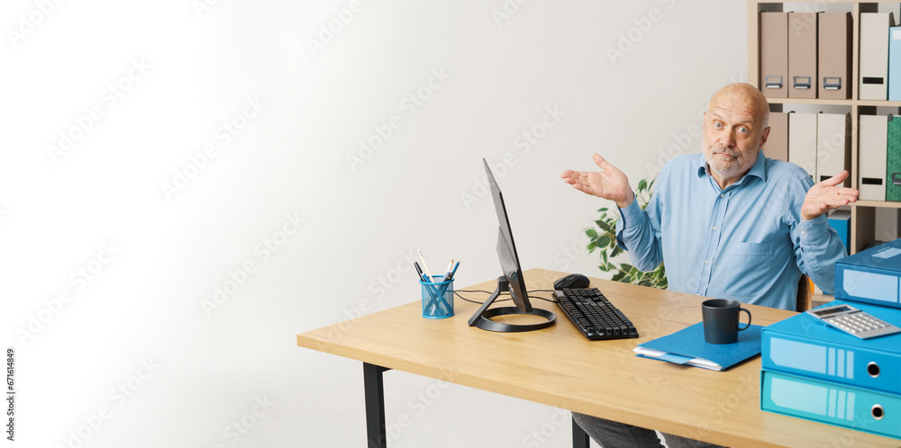 Businessman sitting at the office desk and shrugging, he is sorry and confused