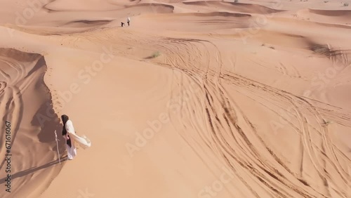 Young bearded man dressed as a shaman dancing on desert sand photo