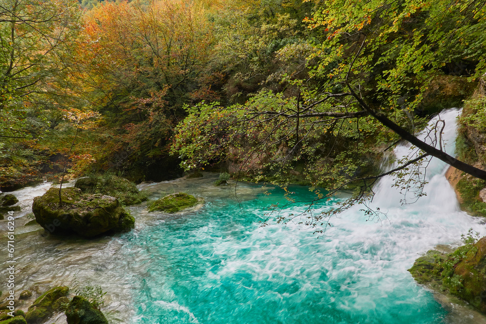 The waterfalls and crystal clear, blue, turquoise and green waters of the Nacedero del Urederra, with its beech forest with its autumn colors in the Sierra de Urbasa-Andía. Navarre. Spain The waterfalls and crystal clear, blue, turquoise and green waters of the Nacedero del Urederra, with its beech forest with its autumn colors in the Sierra de Urbasa-Andía. Navarre. Spain