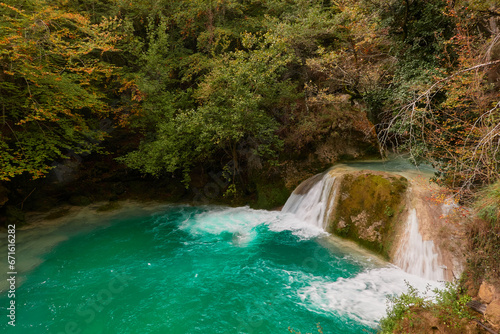 The waterfalls and crystal clear  blue  turquoise and green waters of the Nacedero del Urederra  with its beech forest with its autumn colors in the Sierra de Urbasa-And  a. Navarre. Spain