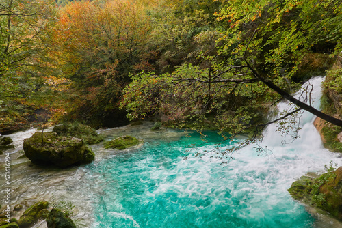 The waterfalls and crystal clear  blue  turquoise and green waters of the Nacedero del Urederra  with its beech forest with its autumn colors in the Sierra de Urbasa-And  a. Navarre. Spain
