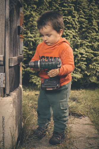 Canvas Print Little boy playing in garden as a craftsman in nice autumn day