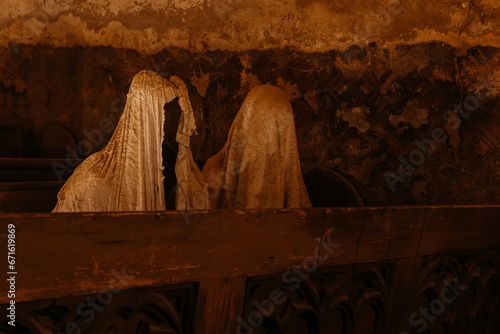 Lukova, Czech Republic, 29 October 2023: Abandoned catholic church of St. George or Jiri, Ghosts line pews, statues by Jakub Hadrava, figures made of plaster, Ghostly figures, Spirit at mass, candle