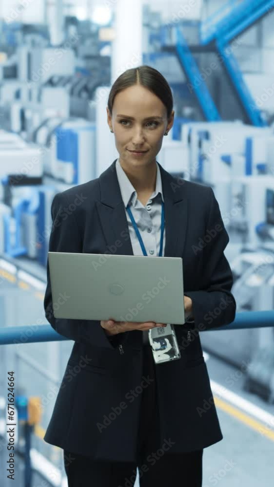 Vertical Screen: Portrait of a Caucasian Female Engineer Using Laptop Computer and Looking Around a Factory Facility with Robotic Arms Producing Modern Electronic Components for Tech Industries Vertical Screen: Portrait of a Caucasian Female Engineer Using Laptop Computer and Looking Around a Factory Facility with Robotic Arms Producing Modern Electronic Components for Tech Industries