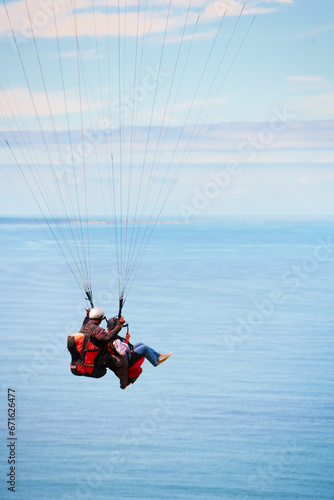Sky, ocean and air with a couple in a parachute together for travel, freedom or adventure. Sea, summer or nature with a man and woman flying over the water while bonding on holiday or vacation