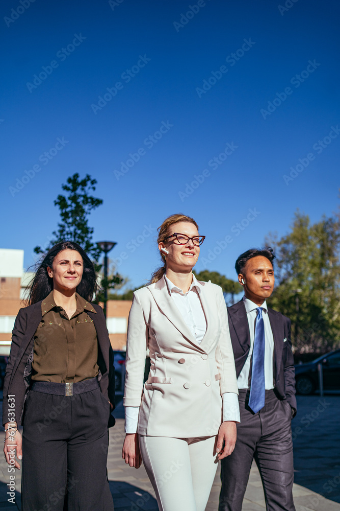 Multiethnic group of smiling business colleagues walking out in the Financial City. Success concept in business Multiethnic group of smiling business colleagues walking out in the Financial City. Success concept in business