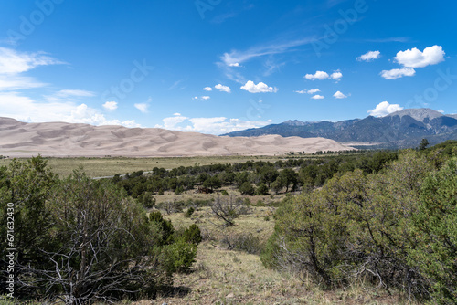 View from the top at Great Sand Dunes National Park in Colorado on a sunny summer day, with mountains in the background