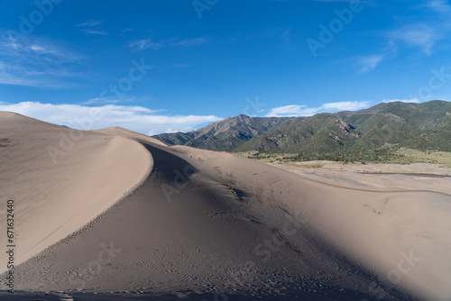 View from the top at Great Sand Dunes National Park in Colorado on a sunny summer day, with mountains in the background © Sitting Bear Media