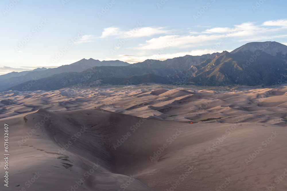 View from the top at golden hour and sunset at Great Sand Dunes National Park in Colorado on a sunny summer evening, with mountains in the background