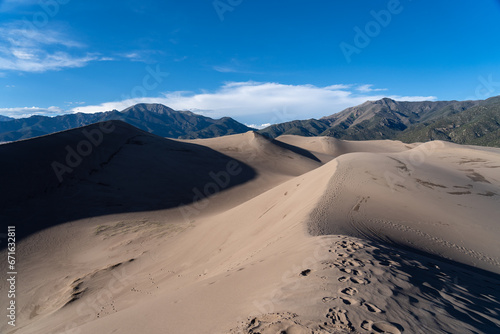 View from the top at golden hour at Great Sand Dunes National Park in Colorado on a sunny summer evening, with mountains in the background