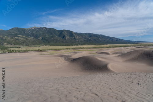 View from the top at golden hour at Great Sand Dunes National Park in Colorado on a sunny summer evening, with mountains in the background