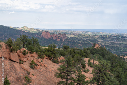 View of mountains, trees, and red rocks from Section 16 and Palmer Loop Hiking Trail in Colorado Springs, CO on a cloudy and overcast summer day - with Garden of the Gods in the background
