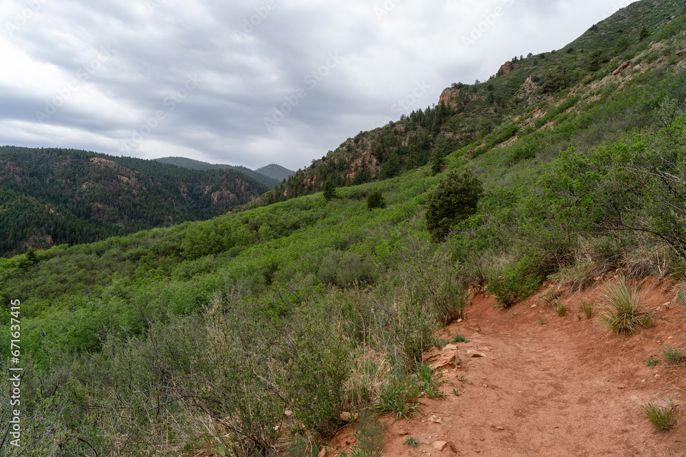 View of mountains, trees, and red rocks from Section 16 and Palmer Loop Hiking Trail in Colorado Spring, CO on a cloudy and overcast summer day View of mountains, trees, and red rocks from Section 16 and Palmer Loop Hiking Trail in Colorado Spring, CO on a cloudy and overcast summer day