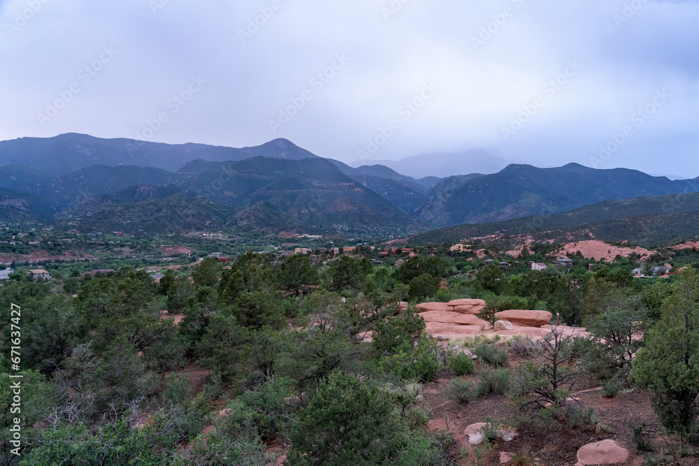 A view of a rainstorm over Pike's Peak and other blue misty mountains on a cloudy summer evening, as viewed from Garden of the Gods in Colorado Springs, CO