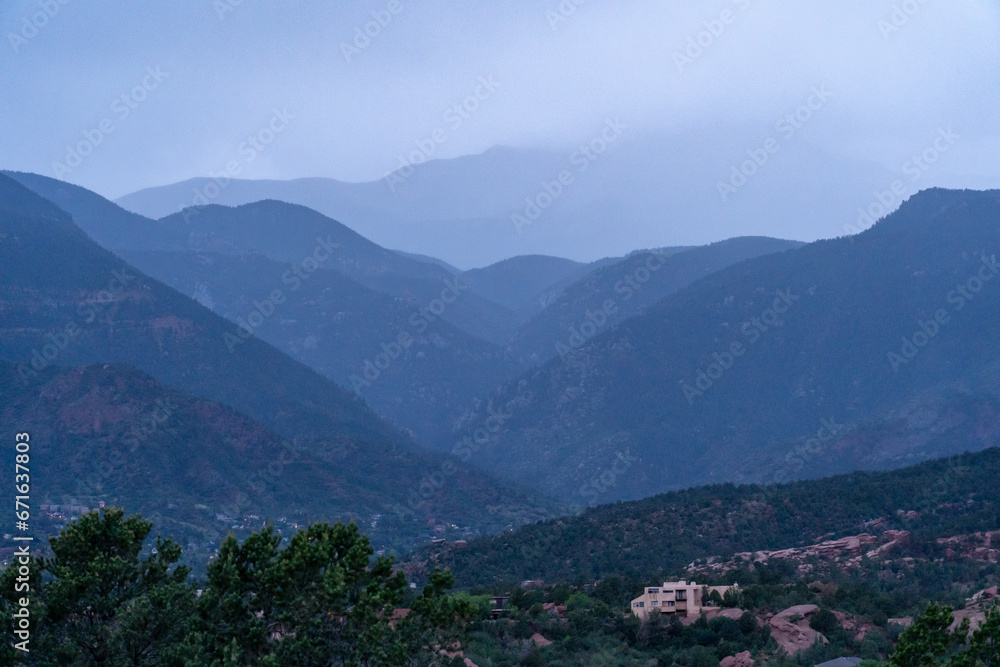 A view of a rainstorm over Pike's Peak and other blue misty mountains on a cloudy summer evening, as viewed from Garden of the Gods in Colorado Springs, CO