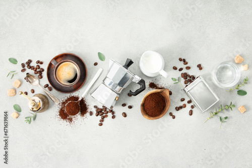 Moka pot, espresso cup, ground coffee, milk, sugar and coffee beans on a grey concrete background photo