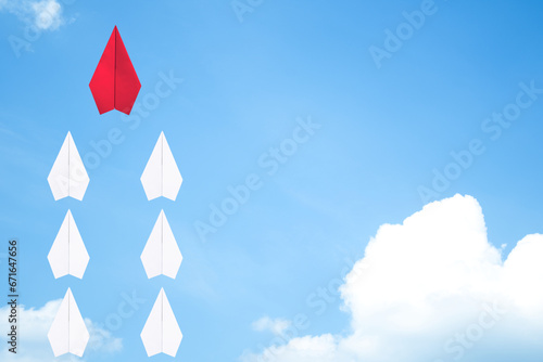 Red paper plane flying leads white paper planes on the sky. The leadership idea for working organizations and businesses. In line paper airplane flying on blue sky with white cloud.